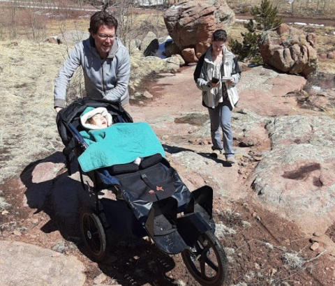 An adult pushes a child in a stroller through difficult terrain